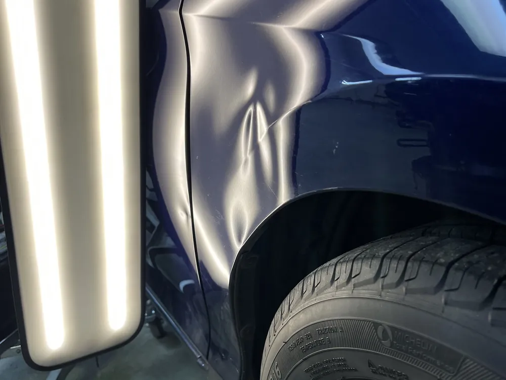 A navy quarter panel under the dent light