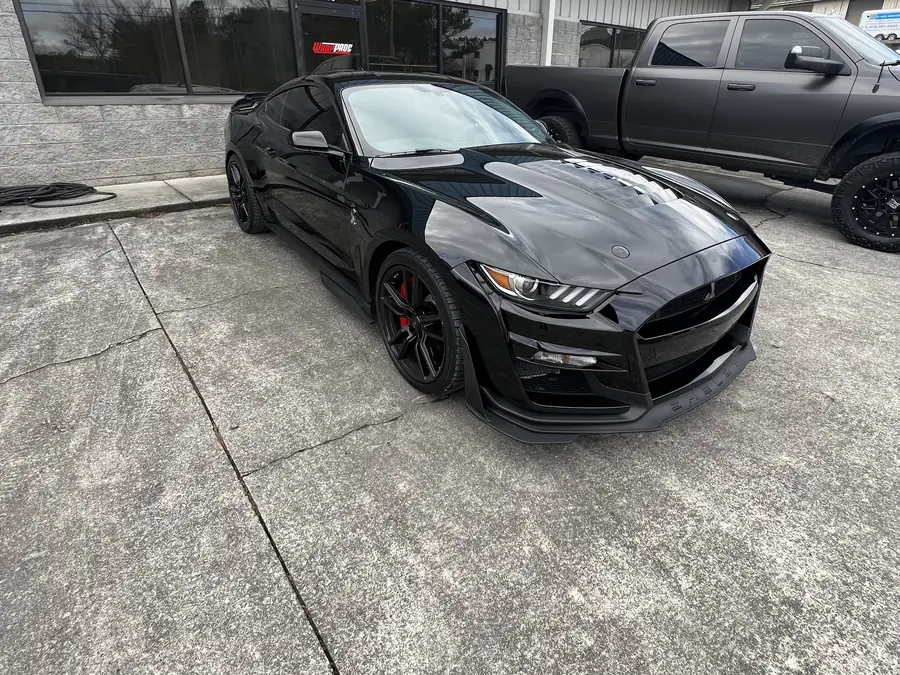 A black Shelby Mustang parked outside the shop
